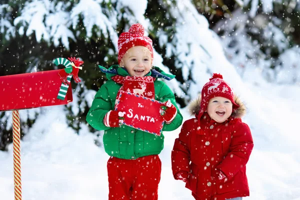 Dítě s dopis do Santa na Vánoce mail box ve sněhu — Stock fotografie