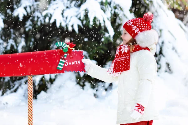 Kind met brief aan de Kerstman bij Kerst mail box in sneeuw — Stockfoto