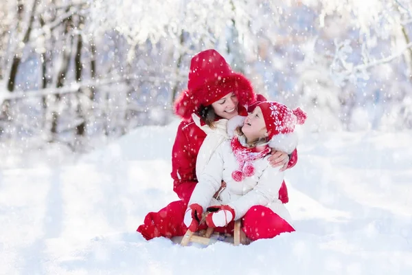 Luge mère et enfant. Amusement hivernal de neige. Famille en traîneau . — Photo