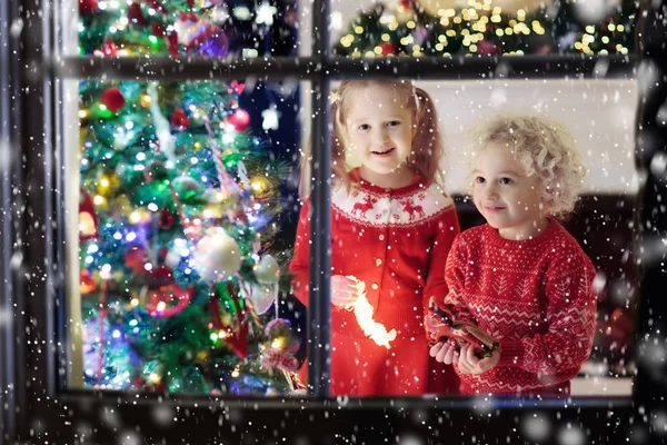 Niños en el árbol de Navidad. Niños en la chimenea en Nochebuena —  Fotos de Stock