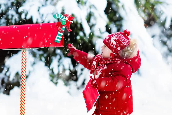 Dziecko z list do Santa w Boże Narodzenie mail box w śniegu — Zdjęcie stockowe