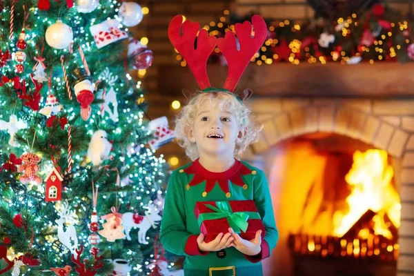 Dítě na vánoční strom a krb na Vánoce — Stock fotografie