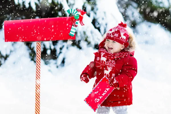 雪のボックスのクリスマス メールでサンタさんへ手紙を持つ子供 — ストック写真