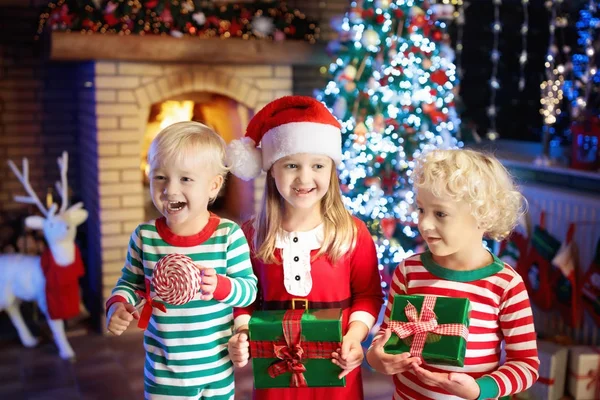 孩子在圣诞树上。孩子在壁炉在圣诞节 — 图库照片