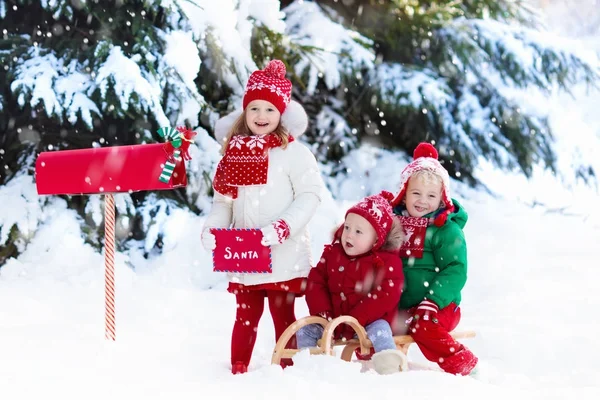 雪のボックスのクリスマス メールでサンタさんへ手紙を持つ子ども — ストック写真