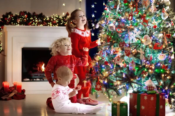 孩子们在圣诞树上。孩子们在圣诞节前夕的壁炉 — 图库照片