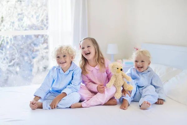 Niño en la cama. Ventana de invierno. Niño en casa por la nieve . — Foto de Stock