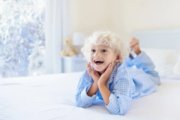 Kid in bed. Winter window. Child at home by snow. — Stock Photo, Image