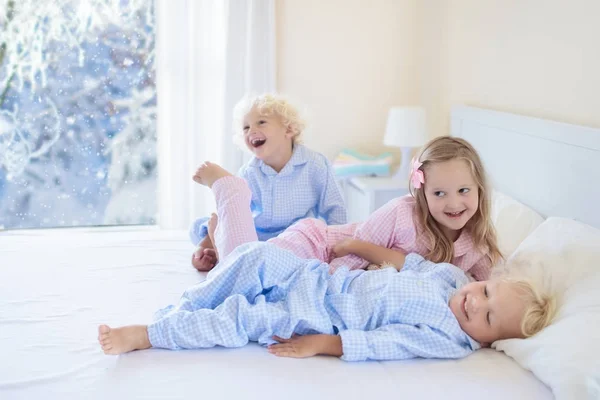 Niño en la cama. Ventana de invierno. Niño en casa por la nieve . — Foto de Stock