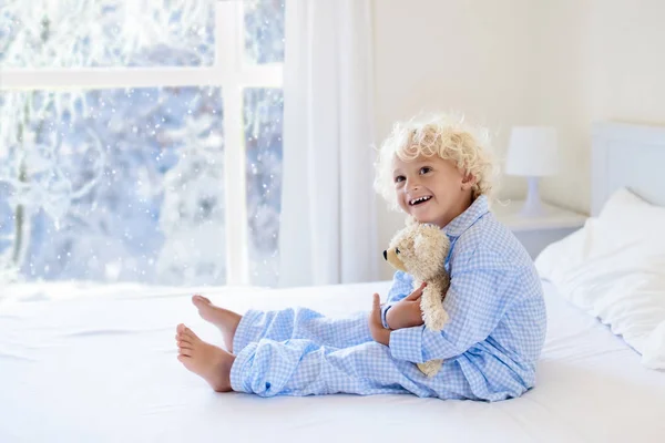 Kid in bed. Winter venster. Kind thuis door de sneeuw. — Stockfoto