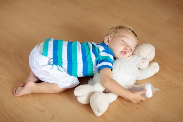 Μωρό στον ύπνο στο πάτωμα με παιχνίδι και το γάλα μπουκάλι. — Φωτογραφία Αρχείου