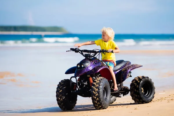 Bambino in quad in spiaggia. Veicolo fuoristrada . — Foto Stock
