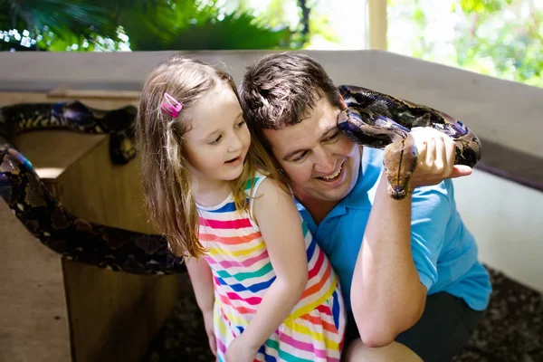 Père et enfant tiennent et nourrissent le serpent python au zoo — Photo