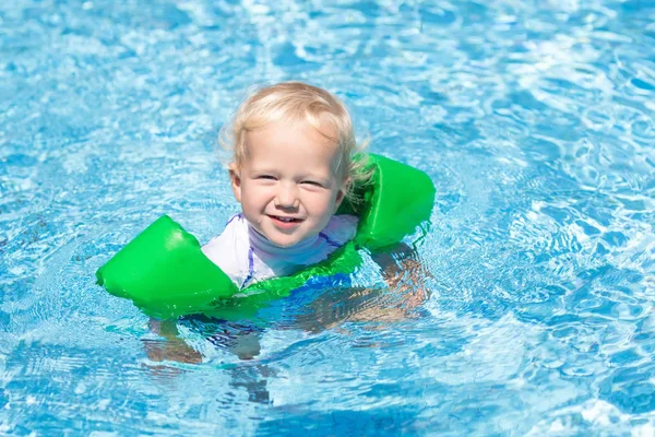 Baby with inflatable armbands in swimming pool.