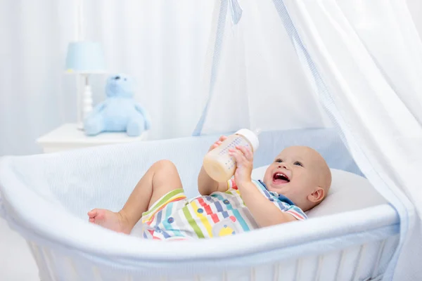 Bebé bebiendo leche. Niño con botella de fórmula en la cama — Foto de Stock