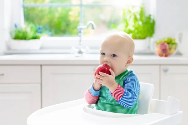 Bambino che mangia mela in cucina bianca a casa — Foto Stock