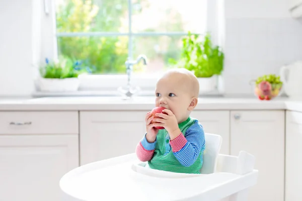 Bambino che mangia mela in cucina bianca a casa — Foto Stock