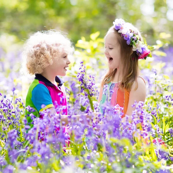Kids with bluebell flowers, garden tools — Stock Photo, Image