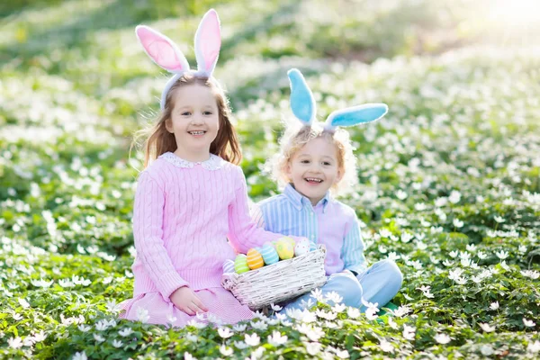 Niños con orejas de conejo en la búsqueda de huevos de Pascua . — Foto de Stock