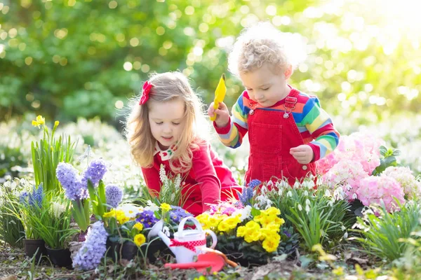 Barnen växt och vatten blommor i vårträdgård — Stockfoto