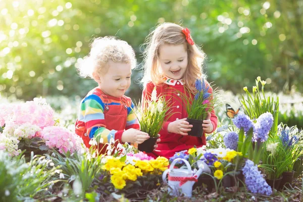 Kinder pflanzen und gießen Blumen im Frühlingsgarten — Stockfoto