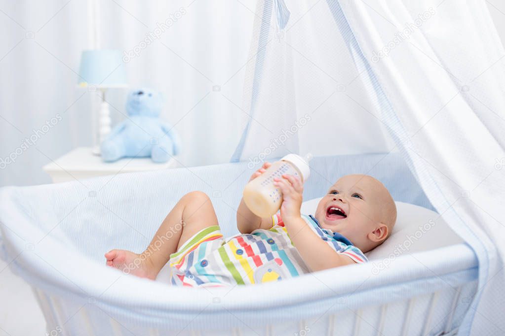 Baby drinking milk. Boy with formula bottle in bed