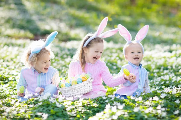 Niños con orejas de conejo en la búsqueda de huevos de Pascua . — Foto de Stock