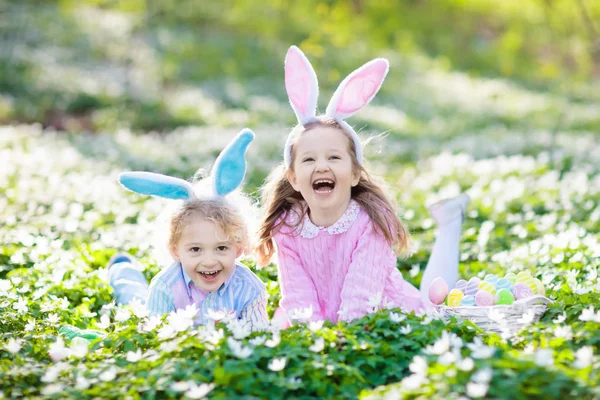 Enfants avec des oreilles de lapin sur la chasse aux œufs de Pâques . — Photo