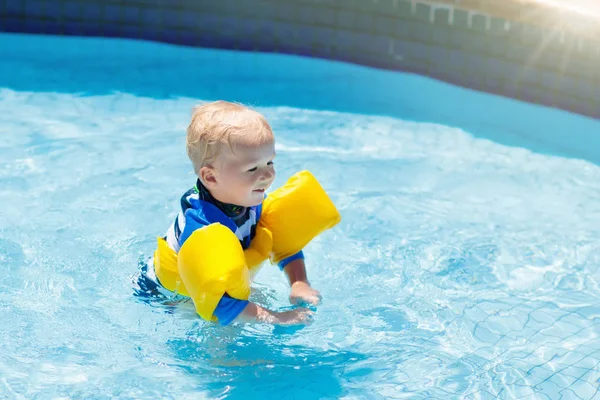 Bebê com braçadeiras infláveis na piscina . — Fotografia de Stock