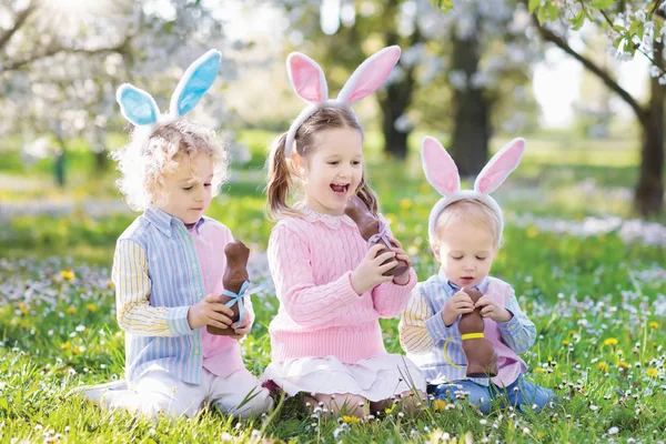 Garden Wielkanoc jajko polować. Dzieci jedzą czekoladowy króliczek. — Zdjęcie stockowe