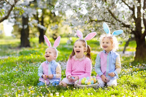Caza de huevos de Pascua. Niños con orejas de conejo y cesta . — Foto de Stock