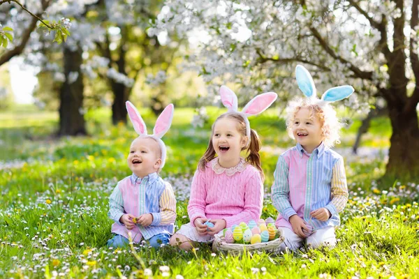 Easter egg hunt. Kids with bunny ears and basket. — Stock Photo, Image