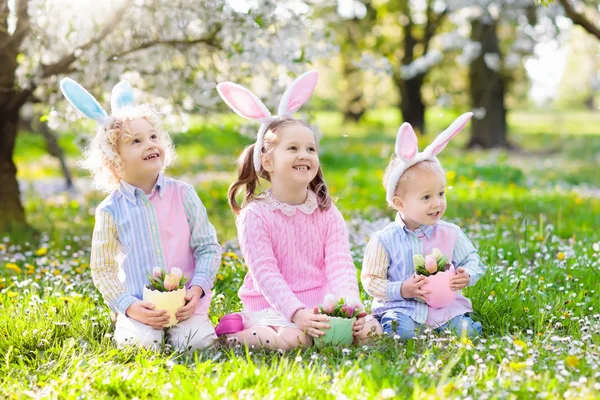 Eieren zoeken met Pasen. Kinderen met bunny oren en mand. — Stockfoto