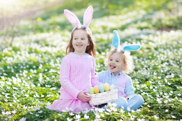 Niños con orejas de conejo en la búsqueda de huevos de Pascua . — Foto de Stock