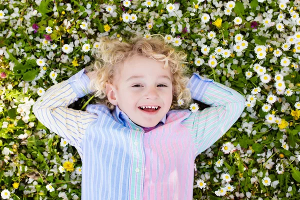 Criança no gramado de grama verde com flores de verão — Fotografia de Stock