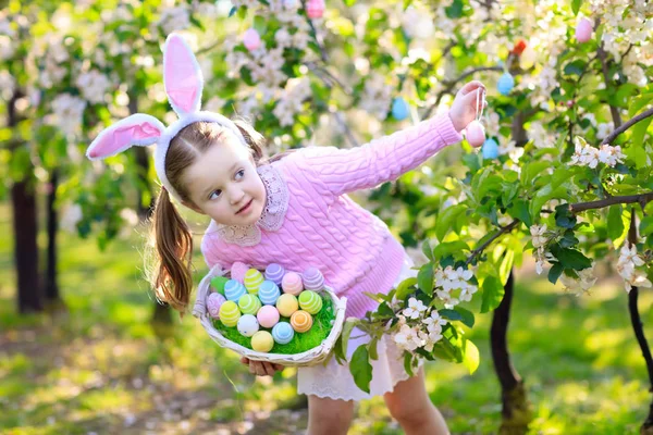 Niño con orejas de conejo en jardín Caza de huevos de Pascua — Foto de Stock