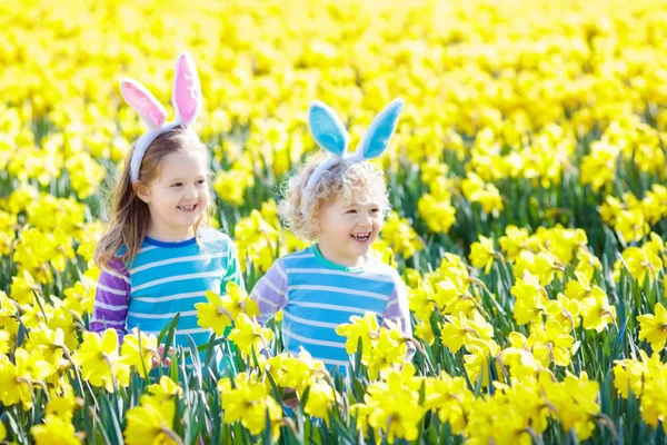 Niños con orejas de conejo en la búsqueda de huevos de Pascua . — Foto de Stock