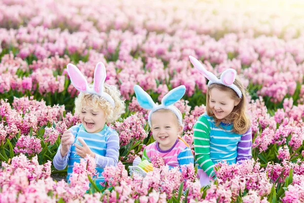Kids on Easter egg hunt in blooming garden. — Stock Photo, Image