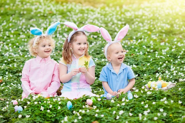 Niños con orejas de conejo en la búsqueda de huevos de Pascua . — Foto de Stock