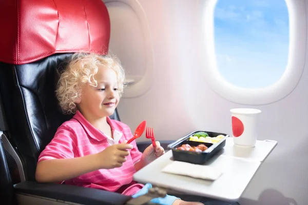 Niño en avión. Los niños vuelan. Comida para niños — Foto de Stock