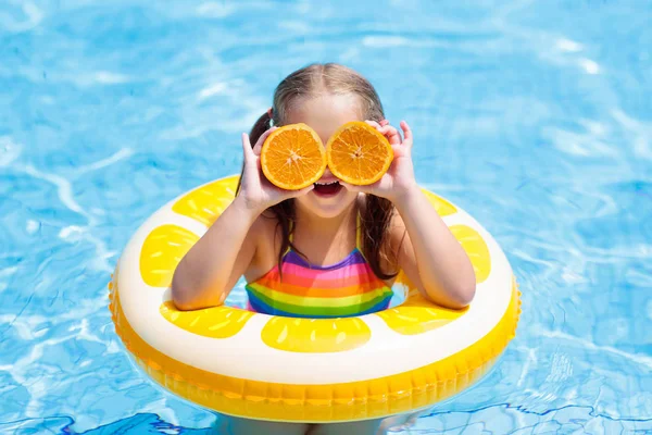 Kind im Schwimmbad. Kind isst Orange. — Stockfoto