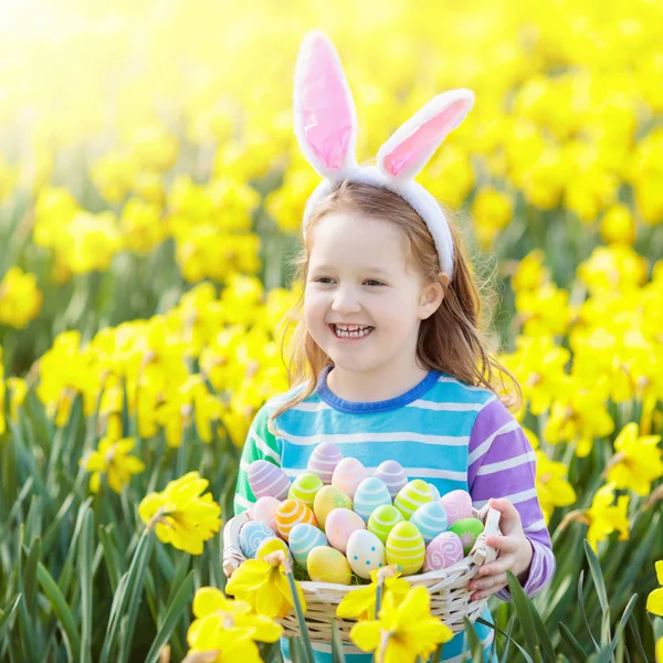 Child with bunny ears on Easter egg hunt