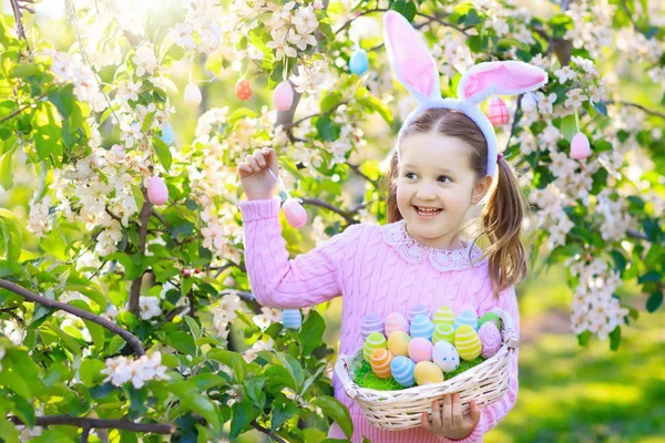 Niño con orejas de conejo en jardín Caza de huevos de Pascua — Foto de Stock