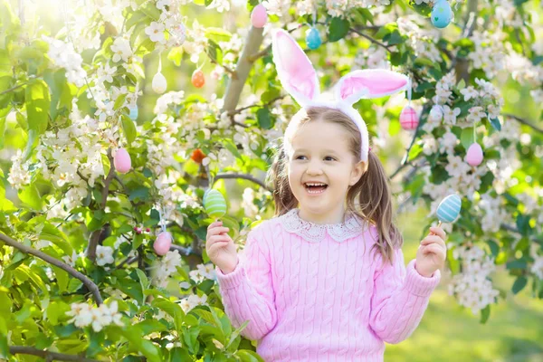 Niño con orejas de conejo en jardín Caza de huevos de Pascua — Foto de Stock