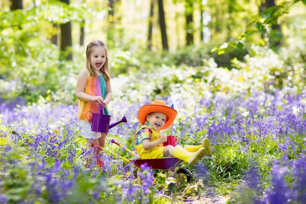 Děti s bluebell květiny, zahradní nářadí — Stock fotografie