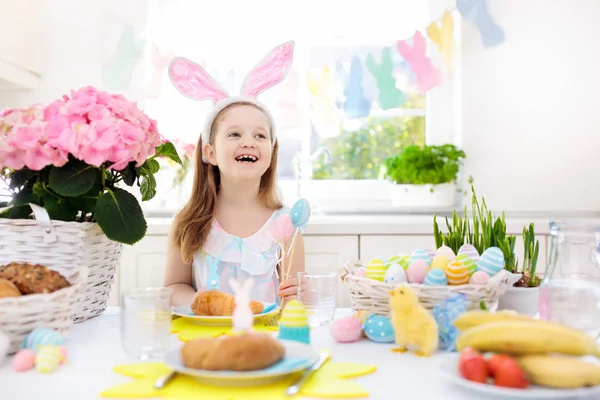 Les enfants au petit déjeuner de Pâques. Panier d'oeufs, oreilles de lapin . — Photo