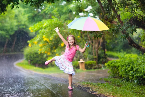 Мальчик с зонтиком играет в летний дождь . — стоковое фото