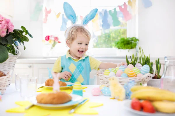 Les enfants au petit déjeuner de Pâques. Panier d'oeufs, oreilles de lapin . — Photo