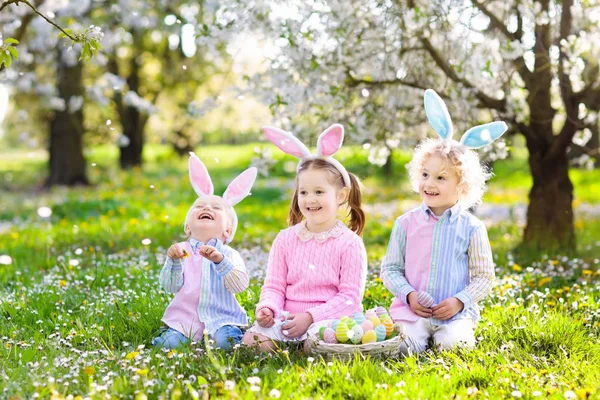 Eieren zoeken met Pasen. Kinderen met bunny oren en mand. — Stockfoto