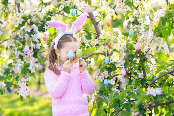 Niño con orejas de conejo en jardín Caza de huevos de Pascua —  Fotos de Stock